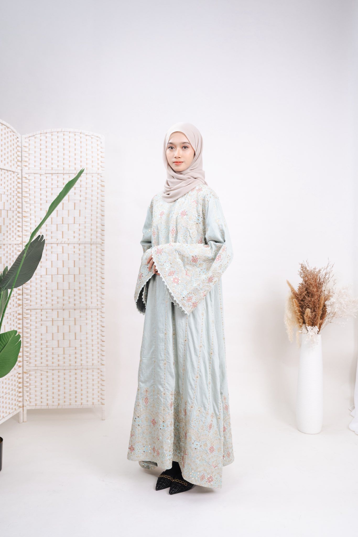 Jalabiya mint pucat dengan sulaman pastel, dipakai model
