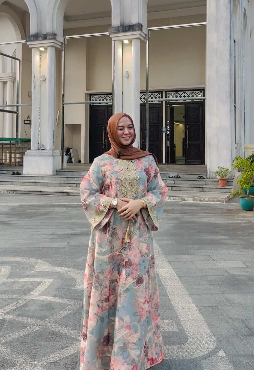 Model memakai jalabiya bercorak bunga pink dan biru dengan renda emas, di serambi masjid